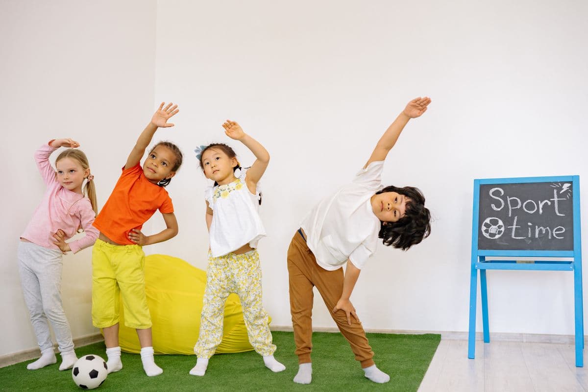 Vaikų grupė atlieka tempimo pratimą Alfa Kids užsiėmime